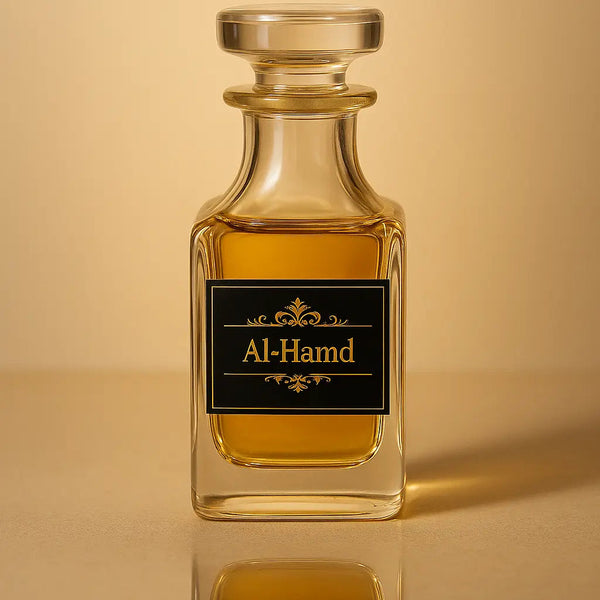 Glass perfume bottle labeled 'Al-Hamd' on a reflective surface with a beige background